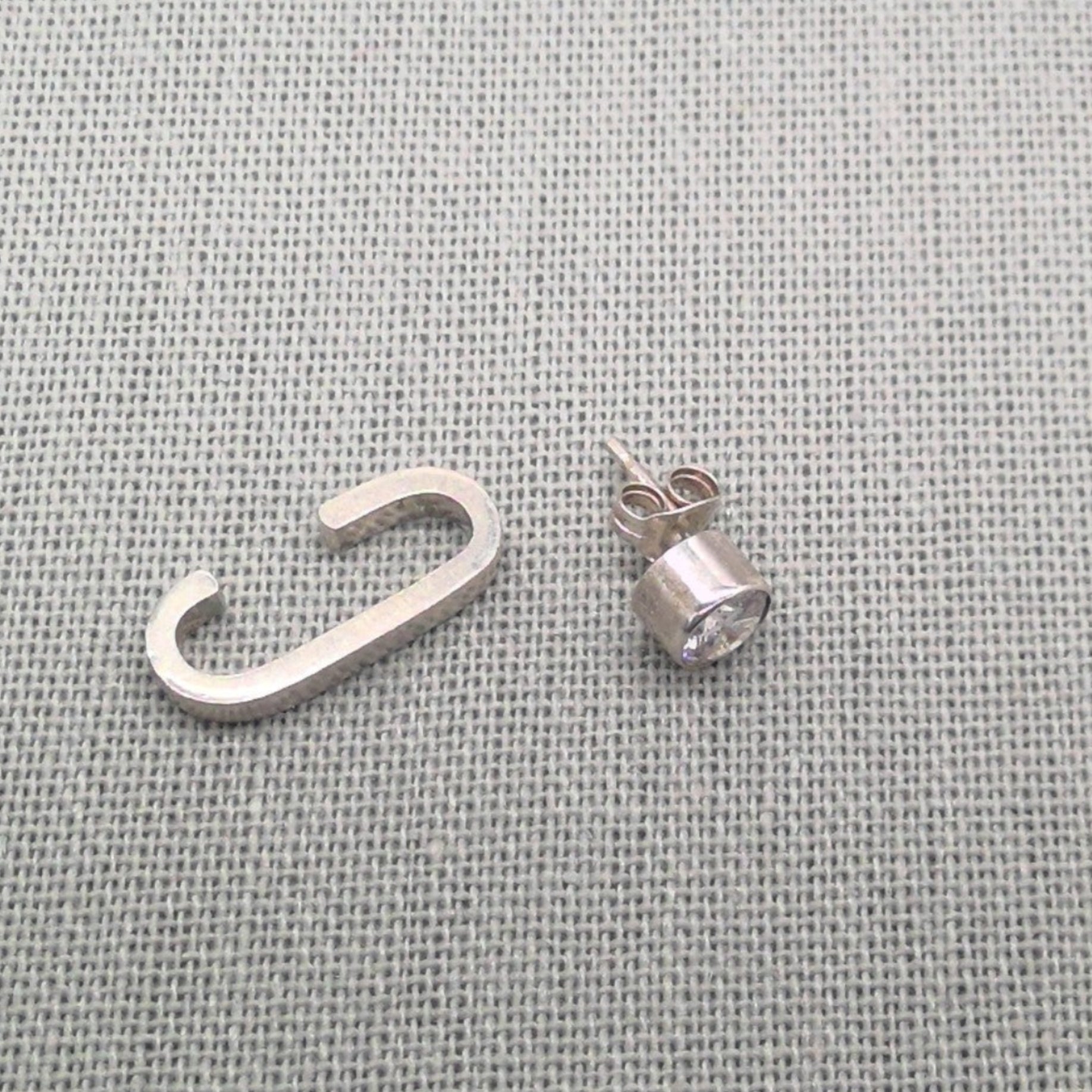 Angled view of silver cuff stripe and zircon stud earrings