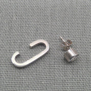 Silver-tone cuff stripe and zircon stud earring pair on fabric