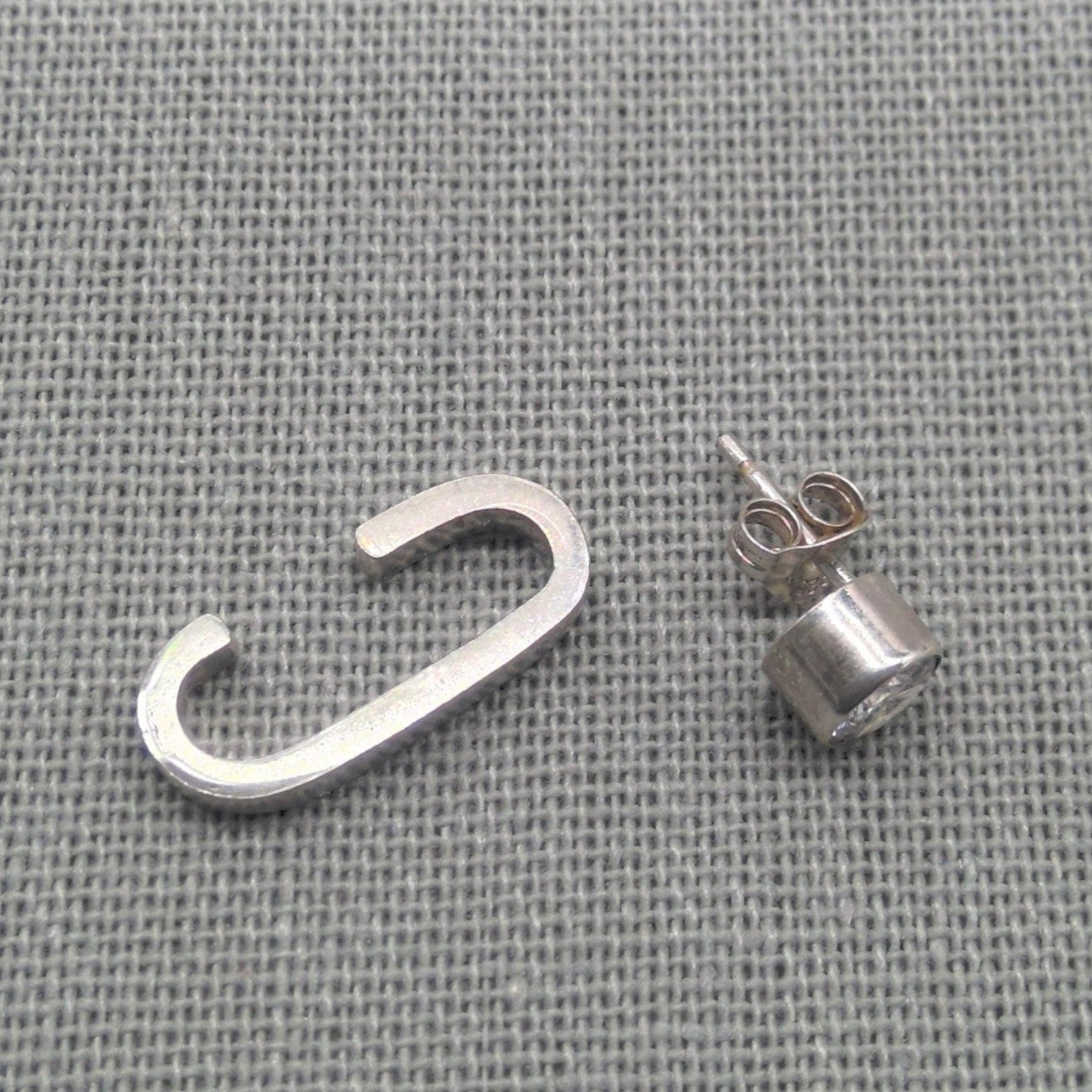 Silver-tone cuff stripe and zircon stud earring pair on fabric
