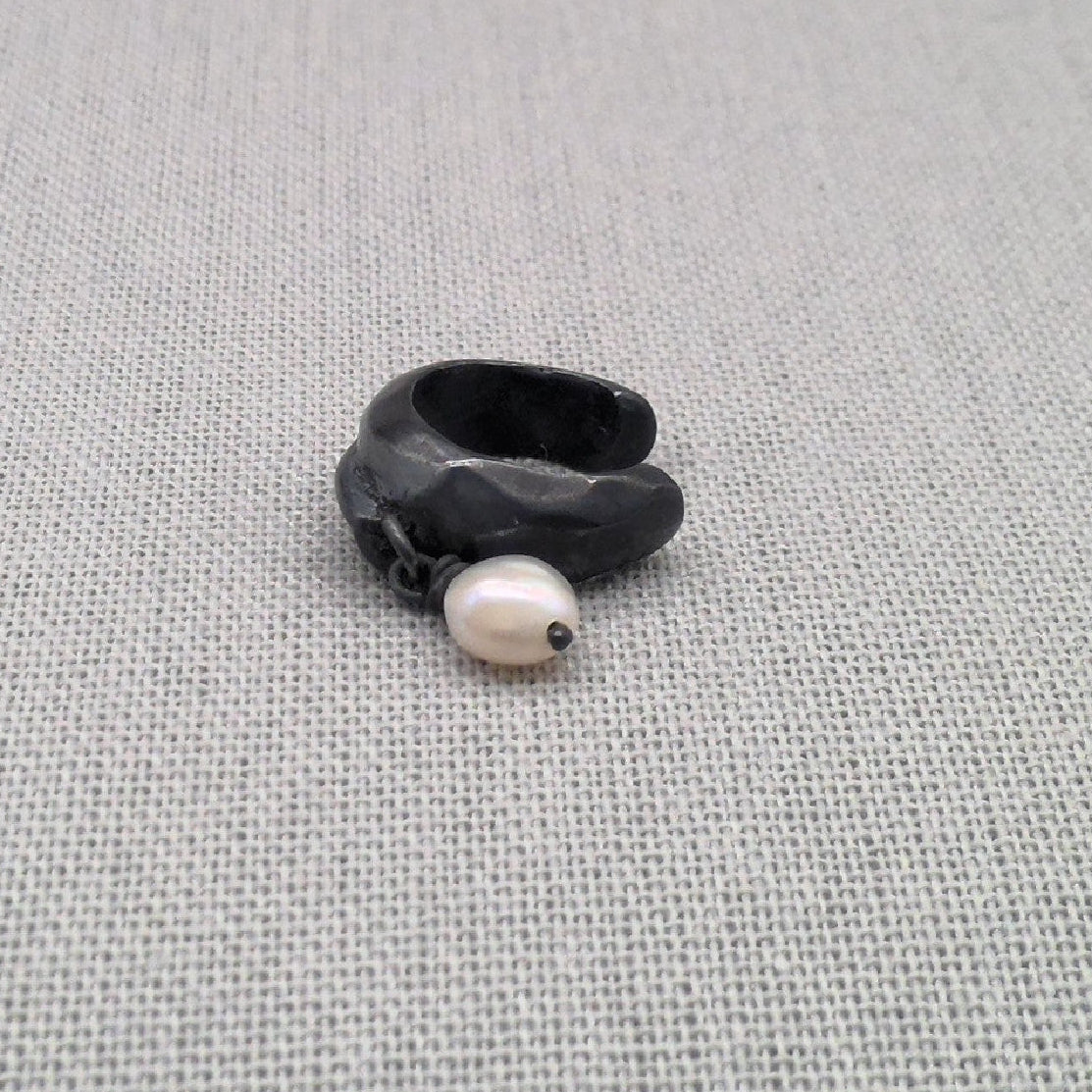 Angled view of black silver ear cuff with freshwater pearl