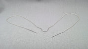 Outline view of sculptural silver face chain on light background