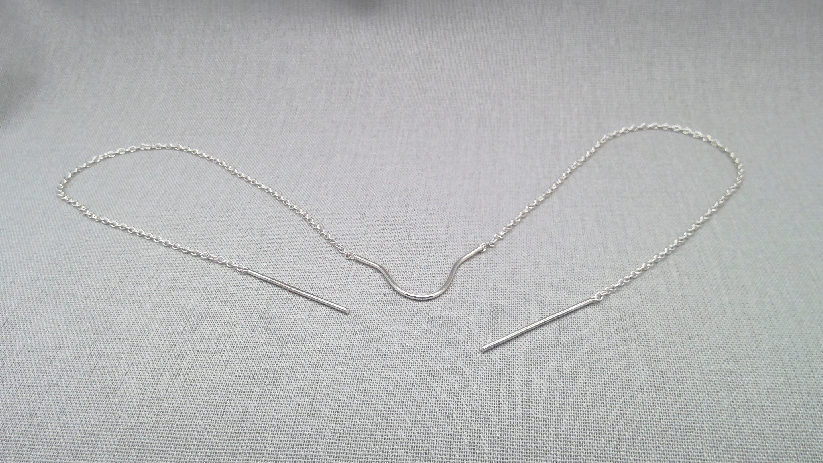 Outline view of sculptural silver face chain on light background