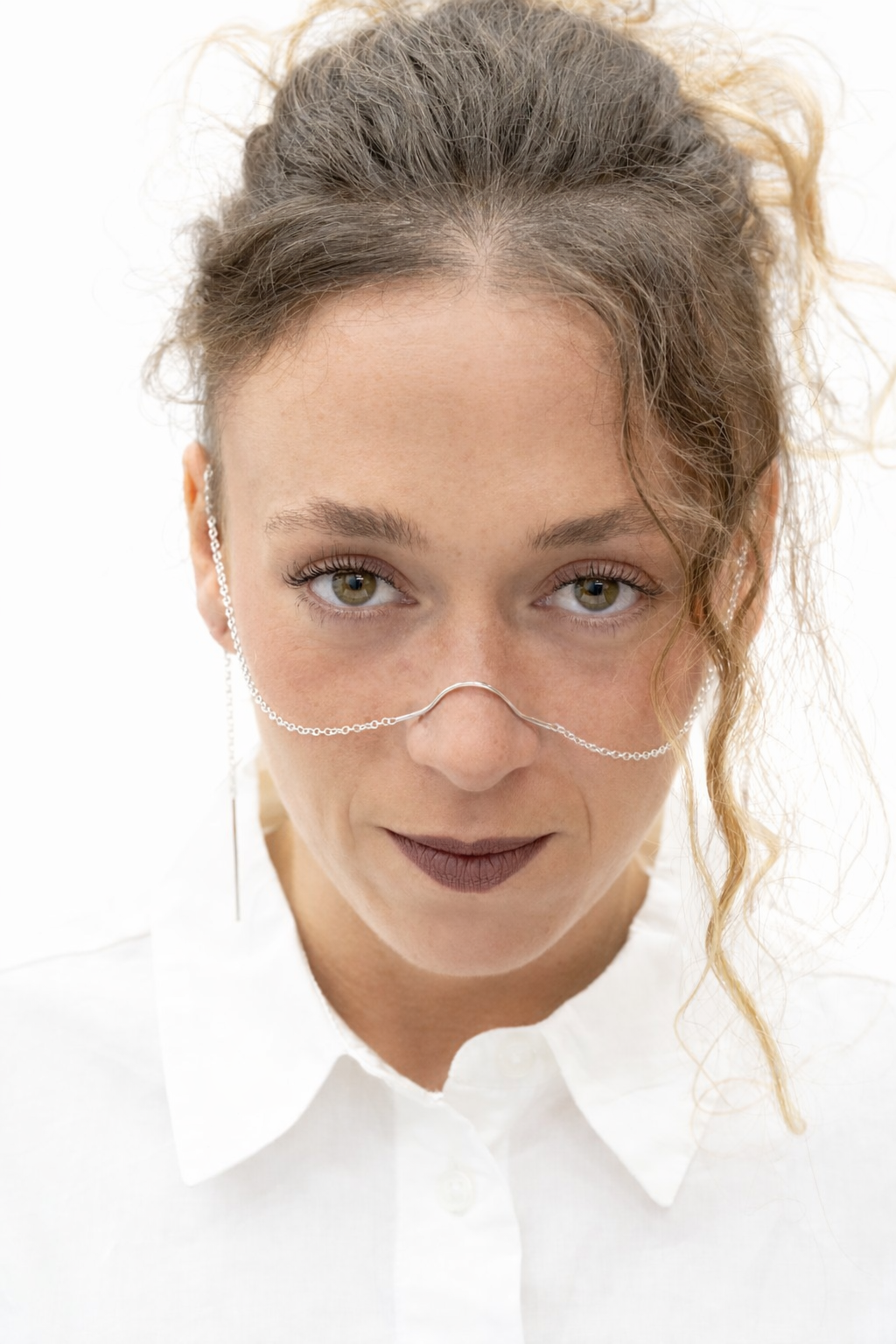 Front view of model wearing sculptural silver face chain