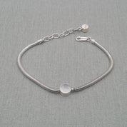Close-up of disc charm on recycled silver snake chain bracelet