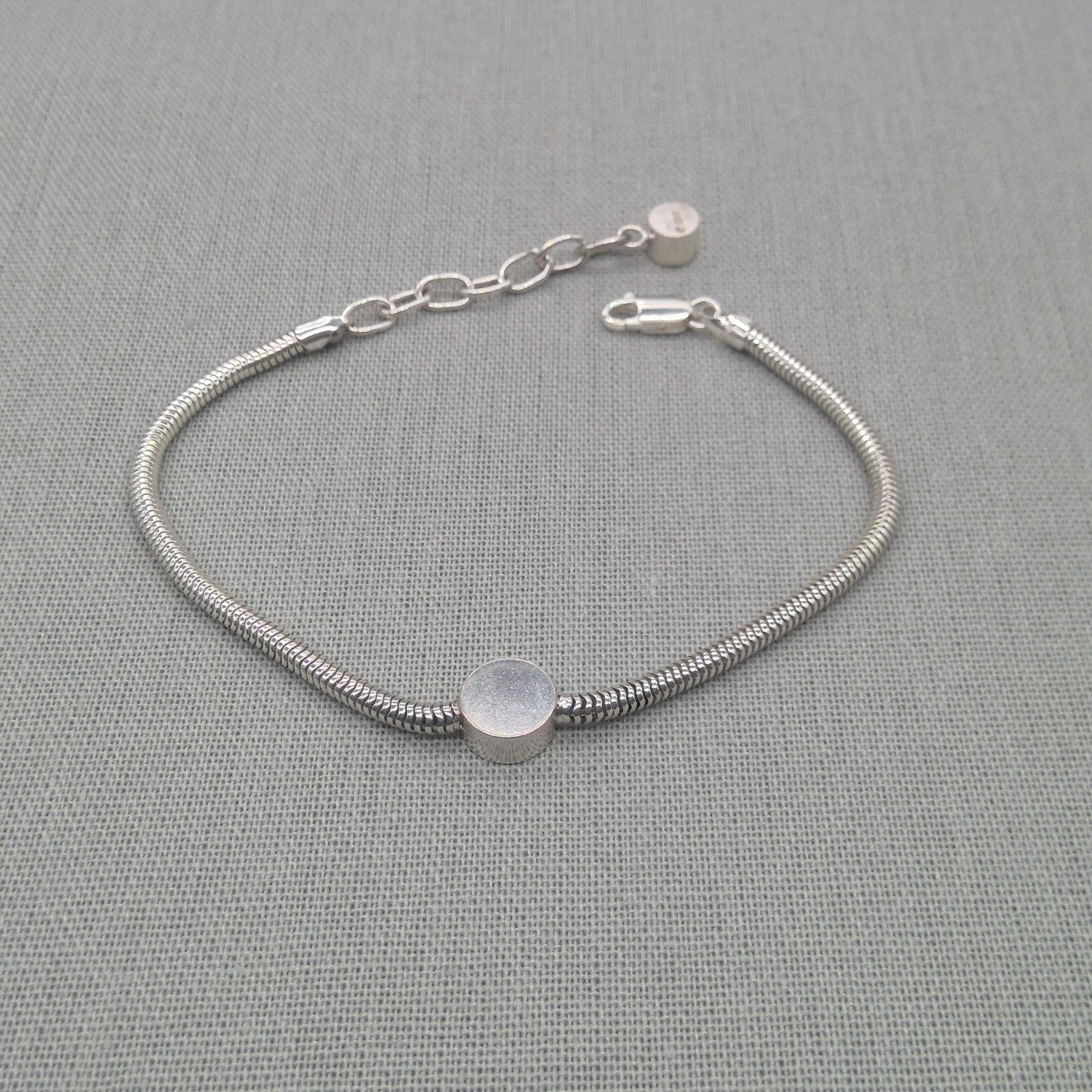 Recycled silver snake chain bracelet with round disc charm on fabric