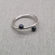 Recycled silver wrap ring with black bead ends on fabric