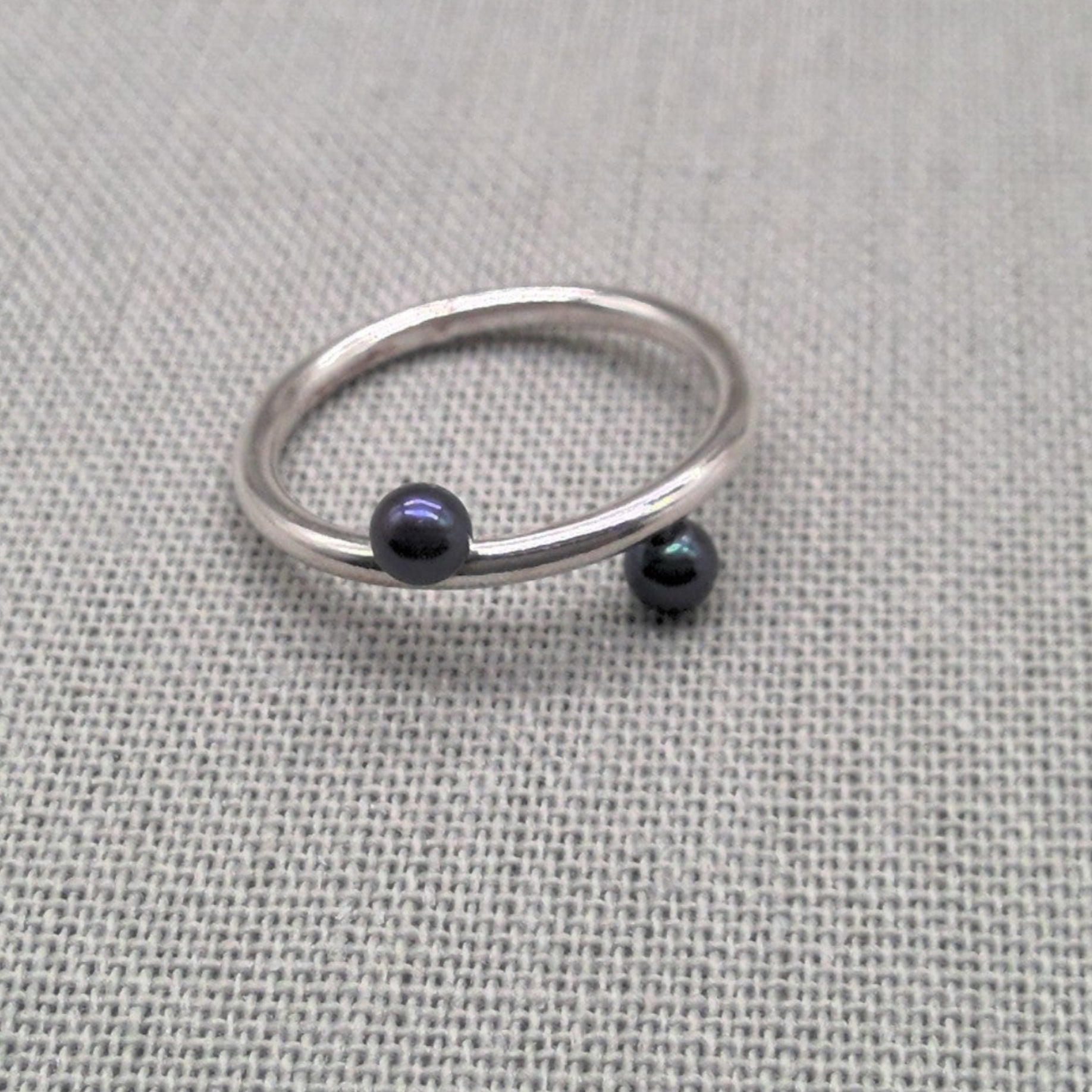 Recycled silver wrap ring with black bead ends on fabric