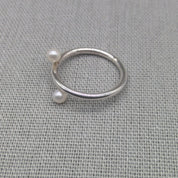 Silver wrap ring with white pearl ends on fabric