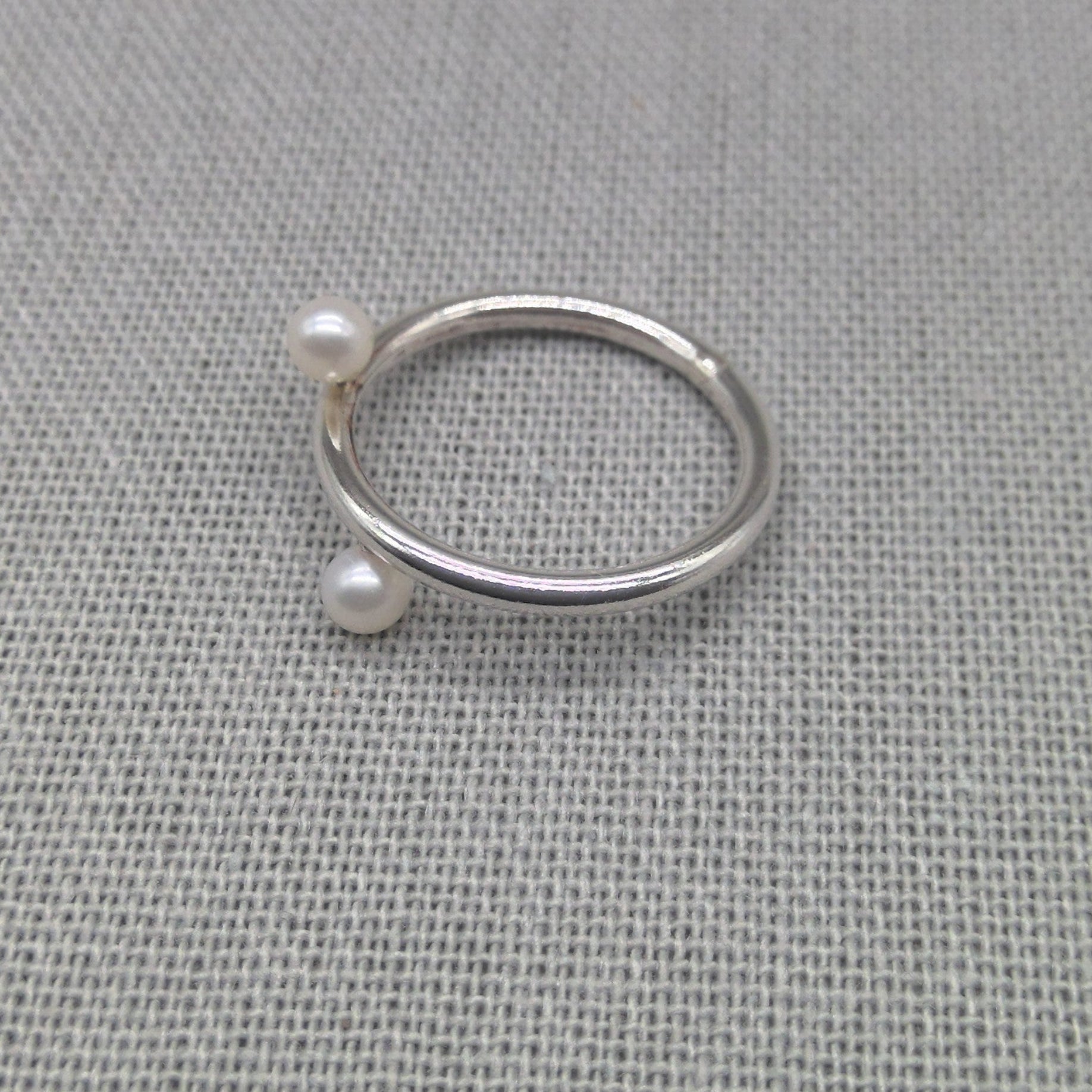 Silver wrap ring with white pearl ends on fabric